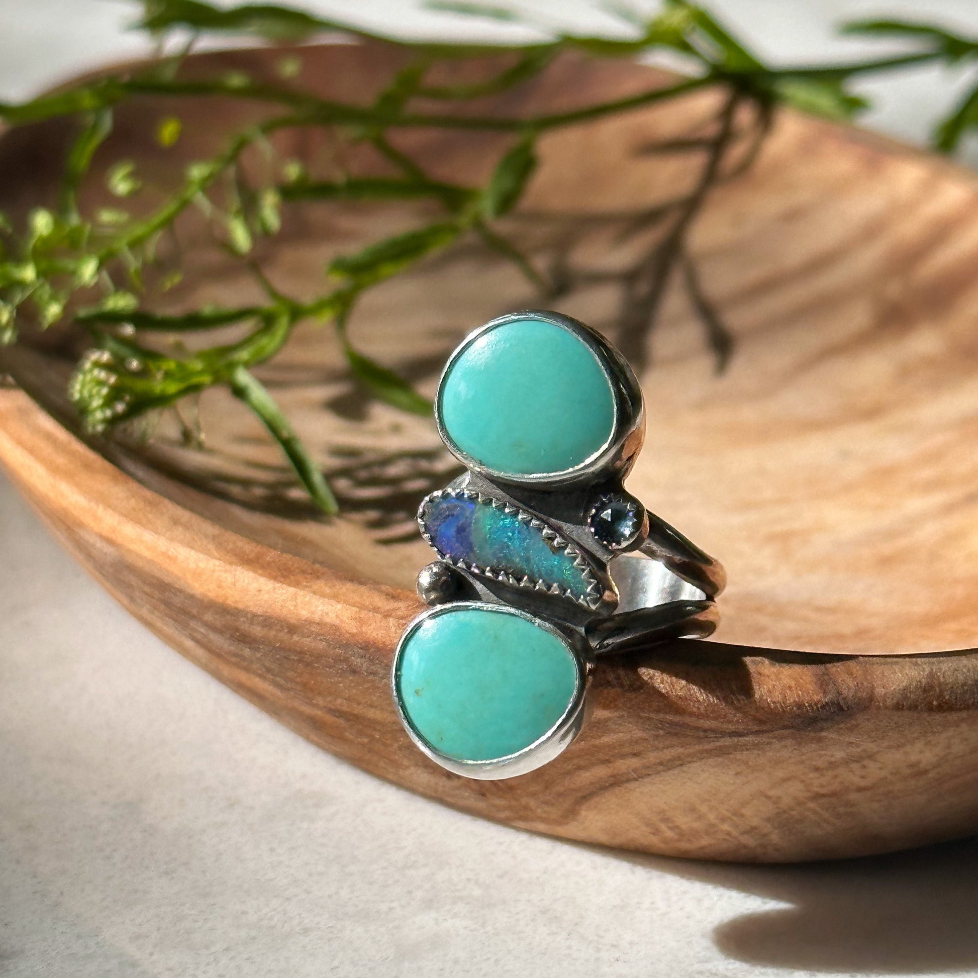 Handcrafted silver ring featuring an oval turquoise stone, set in an intricate bohemian-inspired band, showcasing natural patterns.